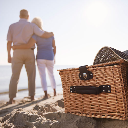 Retired Couple on the beach with a picnic basket
